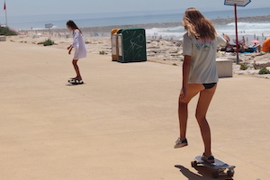 girl skate boarding in beach nomad surf camp - young adults - lisbon - erasmus - university students retreats for adults surf camp lessons children teen summer young adult best nomad kid bali canggu beginners uluwatu france moliets portugal algarve
